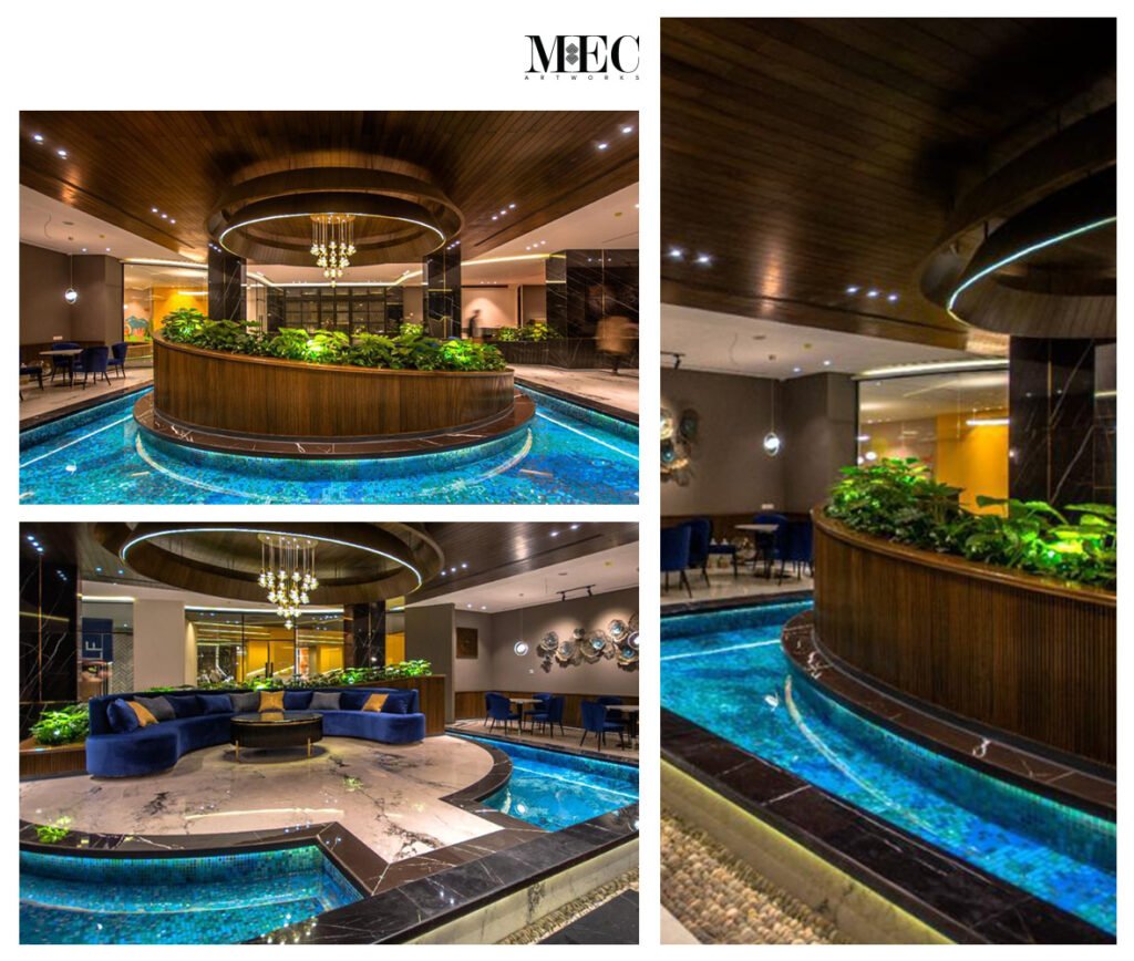 Luxurious indoor lounge with circular blue mosaic water feature, elegant lighting, greenery, and modern architecture.