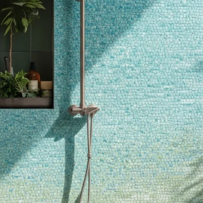 Seafoam green and aqua mosaic tiles in a shower wall reflecting sunlight, creating a serene coastal-inspired spa setting.