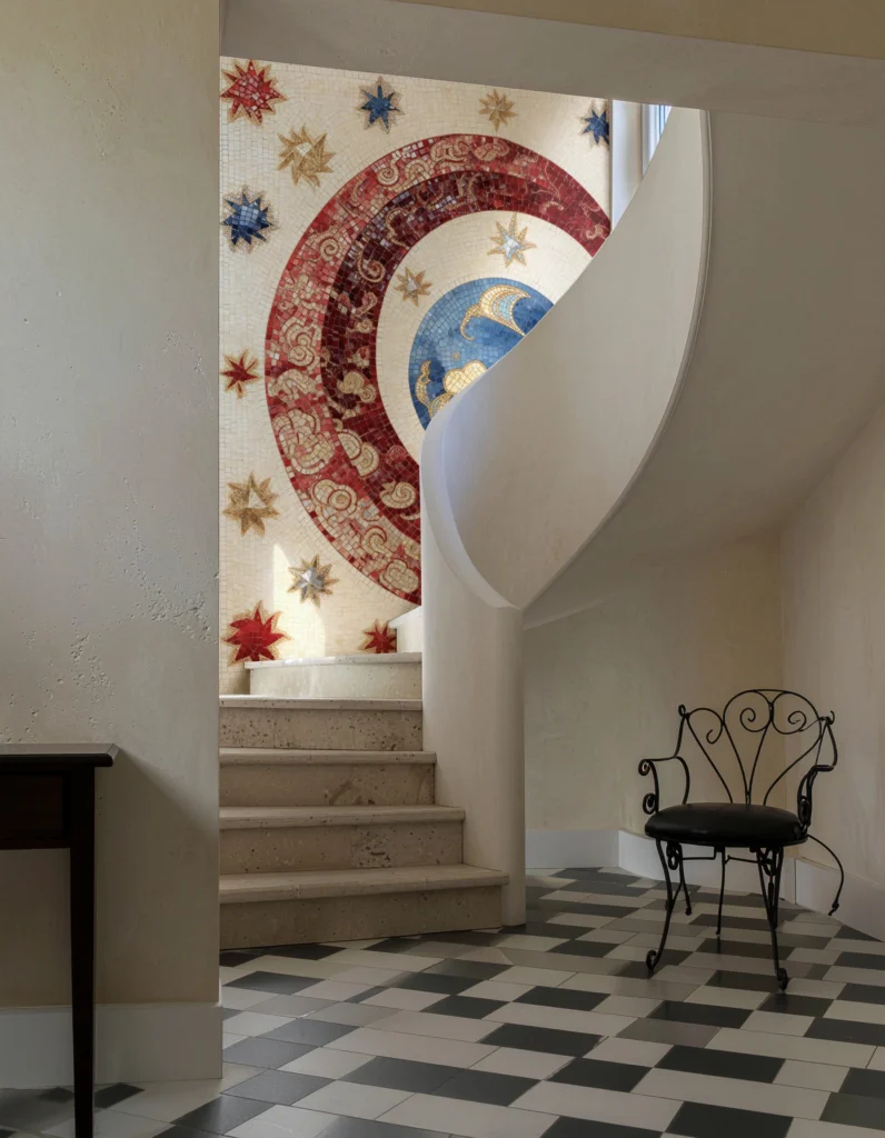 Gold, red, and blue celestial mosaic featuring stars and circular arcs, bringing cosmic elegance to a modern interior staircase.
