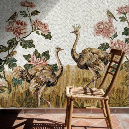 Elegant mosaic wall with two ostriches in golden grass, pink flowers and birds, with one crowned ostrich, beside a woven chair in sunlight.