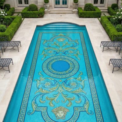 Courtyard pool with classic mosaic medallion and Greek key border in blue and gold, surrounded by stone deck, greenery, and elegant balconies.