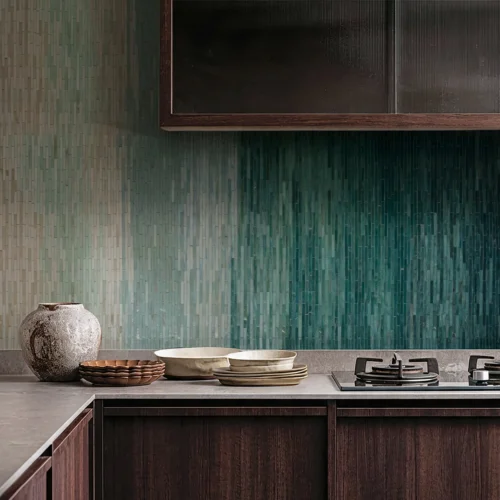 Ombre green linear mosaic tile backsplash with vertical glass strips creating a smooth gradient effect in a modern kitchen interior