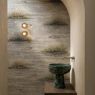 Coastal reeds and fish mosaic wall in neutral tones inside an arched bathroom alcove.