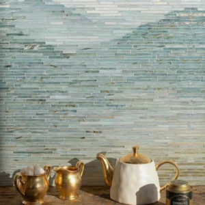 Horizontal seafoam green linear glass mosaic backsplash with brass tea set on wooden counter.