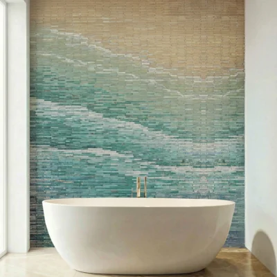 Ombre mosaic bathroom wall with beige to aqua gradient tiles behind a freestanding white bathtub in a modern spa-style interior.
