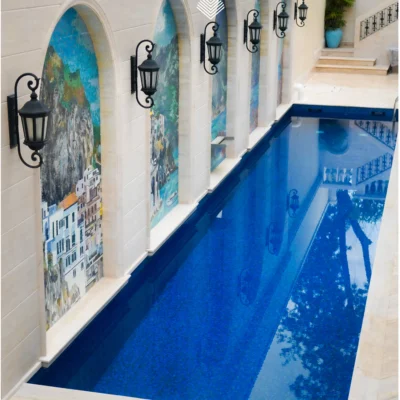 Mediterranean coastal mosaic panels set within arched niches along a luxury indoor pool.