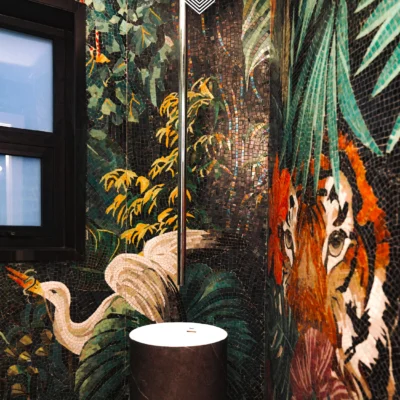Tiger jungle mosaic mural with tropical foliage and bird in a luxury bathroom setting.