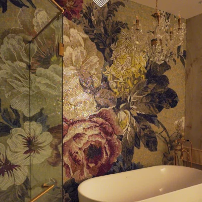 Floral mosaic mural with large blossoms in soft pink and ivory tones installed behind a luxury bathtub.