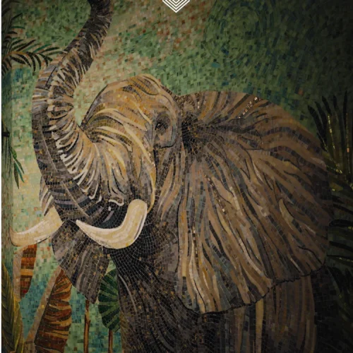 The Majestic Elephant mosaic mural with raised trunk set against an emerald textured background in a luxury interior.