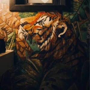 Majestic Tiger mosaic mural with jungle leaves in warm orange and green tones installed on a bathroom wall.