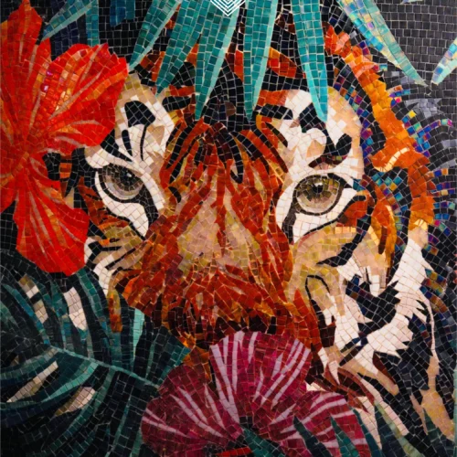 Colorful tiger face mosaic mural with tropical leaves and red flowers on a dark background.