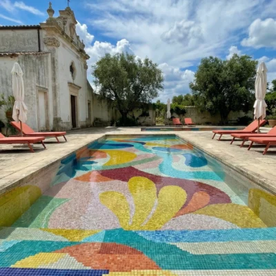 Abstract multicolor pool mosaic with flowing shapes in turquoise, yellow, coral, and blue tones.