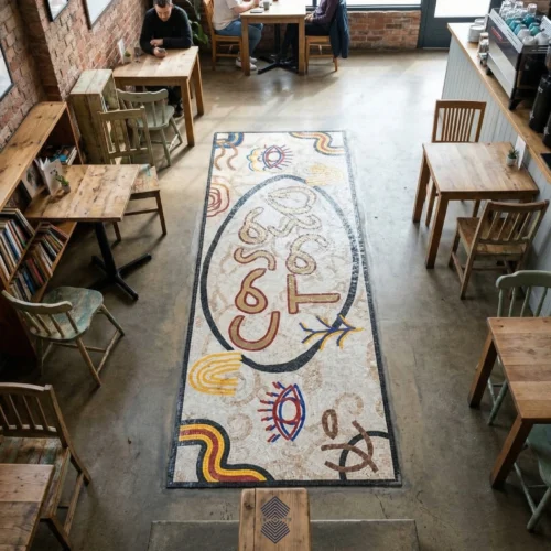 Long abstract mosaic floor runner with Casa Tasa lettering in a café setting.