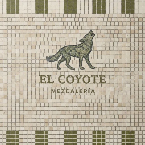Mosaic signage featuring a green coyote figure with “El Coyote Mezcalería” text on an ivory tile background.