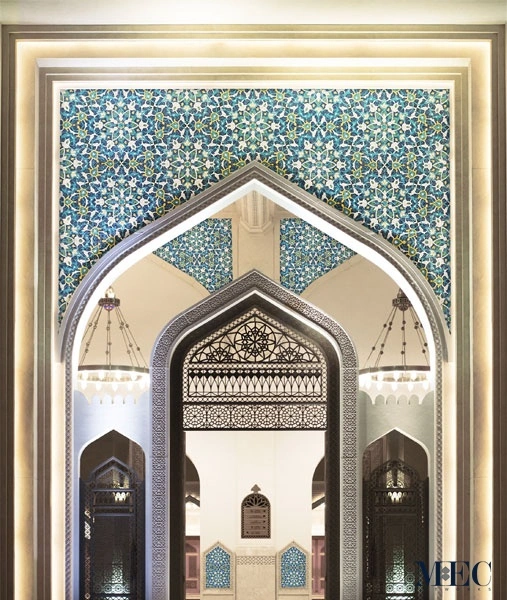 Islamic arch with intricate blue floral and geometric mosaic patterns, showcasing traditional mosque interior design and detailed architectural symmetry.