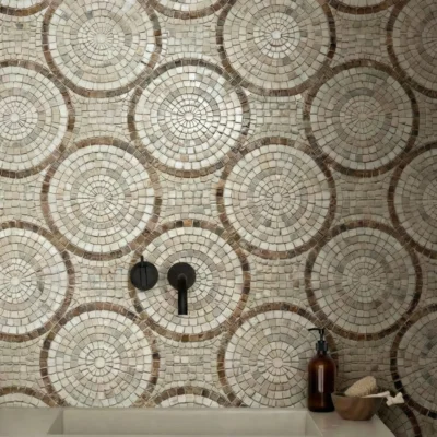 Mosaic tile wall with repeating concentric circular medallions in beige and taupe stone tones.