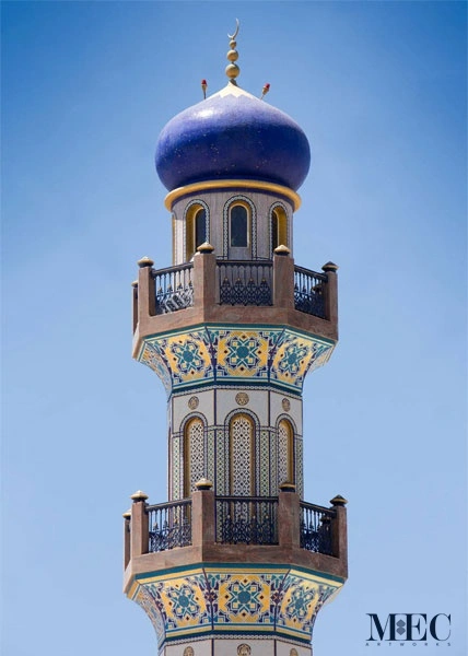 Islamic minaret with blue dome and intricate mosaic bands featuring geometric and floral patterns inspired by traditional mosque architecture.