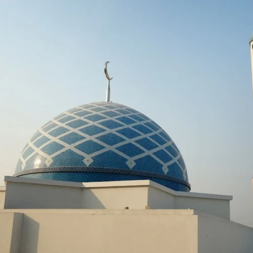 Blue mosque dome with white geometric lattice mosaic pattern and crescent finial, paired with a minimalist minaret in modern Islamic architecture.