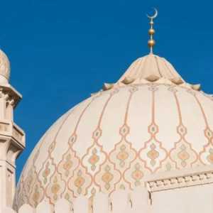 Beige mosque dome with subtle Islamic ornamental mosaic patterns and crescent finial, showcasing elegant traditional architectural design.