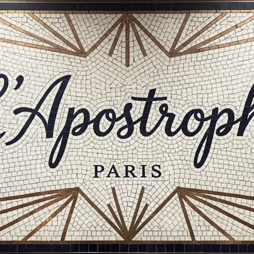Mosaic sign with “L’Apostrophe Paris” text, Art Deco starburst pattern, and ivory background.