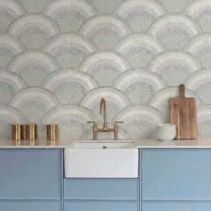 Soft blue mosaic wall with repeating scalloped wave pattern in light grey and ivory tones behind a kitchen sink.