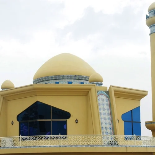 Beige mosque dome and minaret with subtle Islamic mosaic detailing and geometric accents reflecting modern and traditional architectural design harmony.