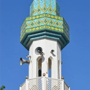 Turquoise mosque minaret with geometric mosaic patterns in blue and yellow, topped with crescent finial reflecting traditional Islamic architecture.