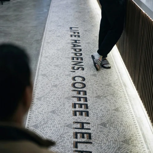 Long mosaic floor runner with “Life Happens Coffee Helps” text in a café setting.