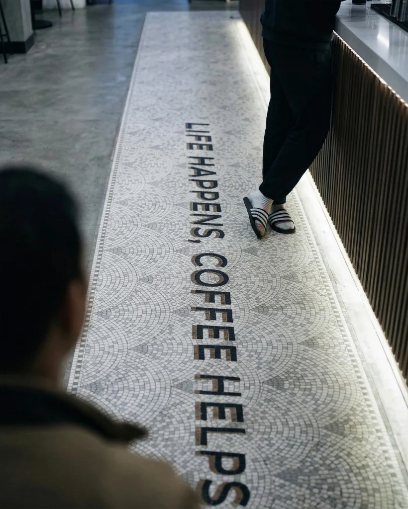 Long mosaic floor runner with “Life Happens Coffee Helps” text in a café setting.