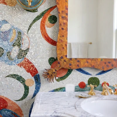 Colorful mosaic bathroom wall with flowing geometric patterns in blue, coral, green, and terracotta tones.