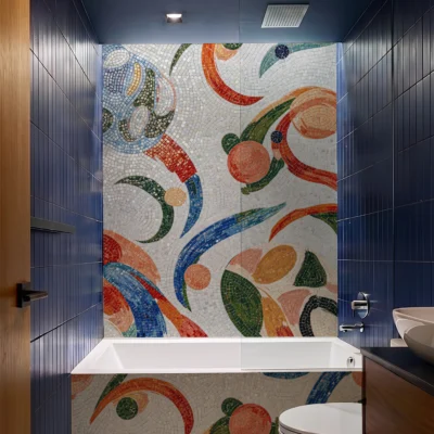 Colorful abstract mosaic bathroom wall and floor with flowing geometric patterns in blue, coral, green, and terracotta tones.
