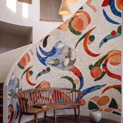 Curved abstract mosaic wall with colorful geometric patterns flowing along a luxury staircase in a contemporary interior.