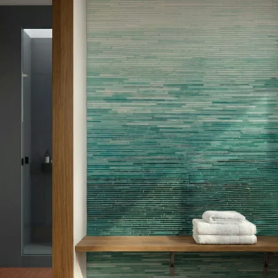 Ombre glass mosaic wall tile with layered aqua and deep teal tones in a sleek linear pattern inspired by ocean horizons.