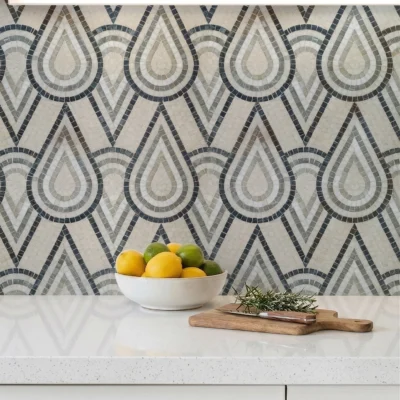 Grey and ivory geometric mosaic tile backsplash with layered teardrop patterns in a modern Art Deco inspired design.