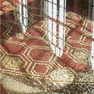 Luxury handcrafted pool mosaic featuring a crimson geometric medallion design with gold hexagonal patterns beneath water reflections.