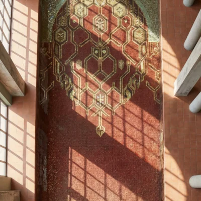 Luxury handcrafted pool mosaic featuring a crimson geometric medallion design with gold hexagonal patterns beneath water reflections.