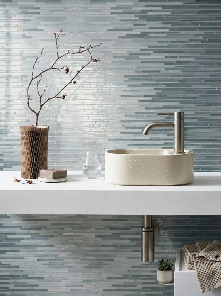 Linear aqua glass mosaic wall tile in soft blue and grey tones creating a calm modern bathroom and spa-inspired interior.