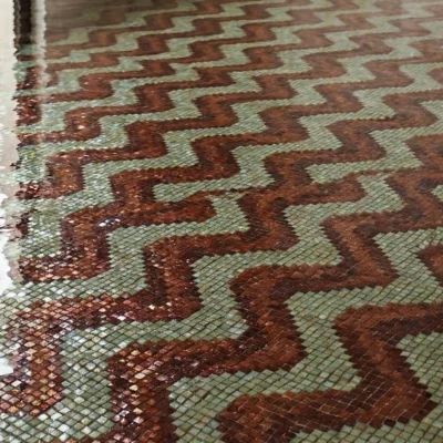 pool mosaic featuring flowing terracotta zigzag patterns with earthy tones beneath reflective water.