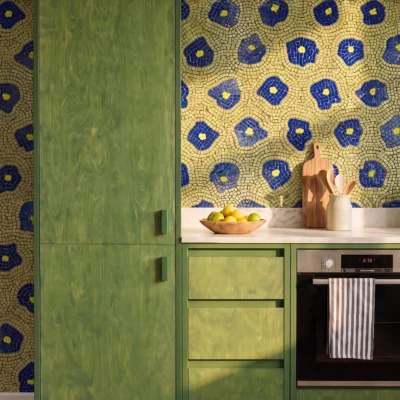 Handcrafted mosaic tile with cobalt blue floral motifs on an olive-green background used as a decorative kitchen backsplash wall.