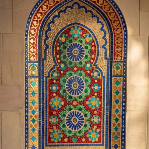 Handcrafted Moroccan arch mosaic featuring colorful rosette medallions in blue, green, red, and gold within a traditional Islamic niche.