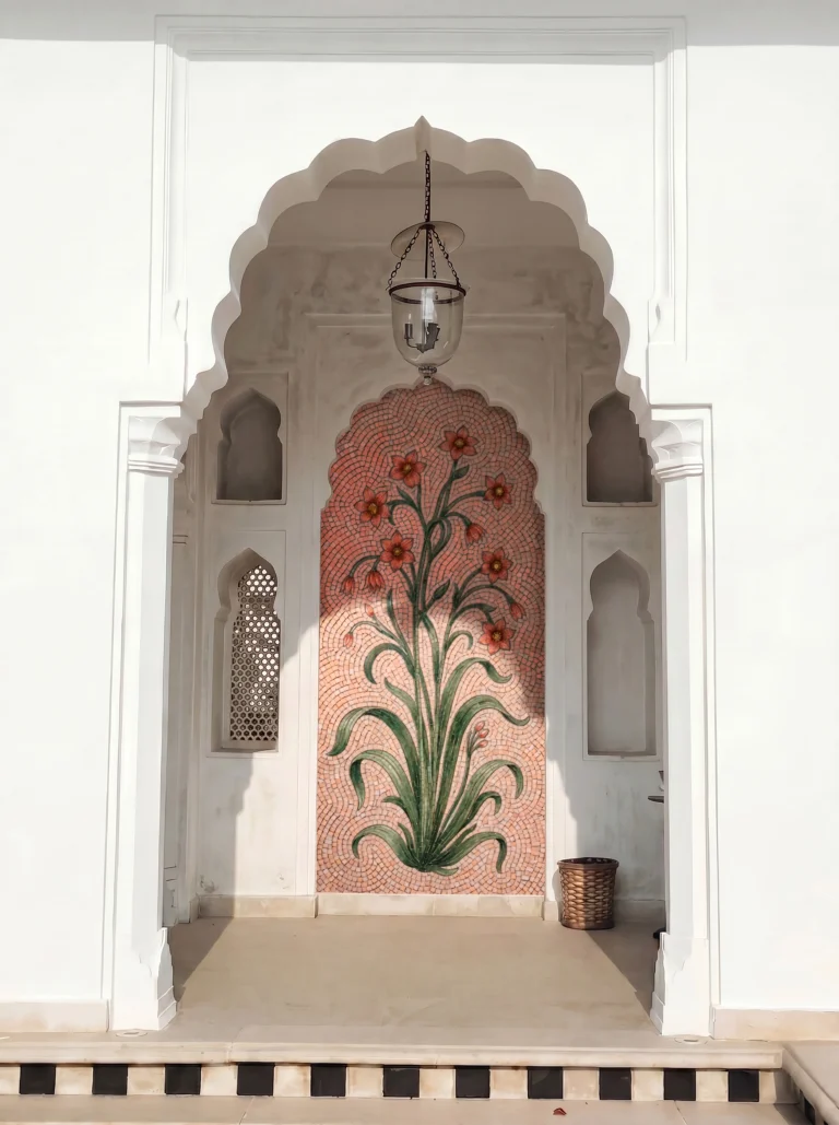 Handcrafted floral mosaic niche featuring blooming flowers and flowing green foliage on a soft pink background within a Mughal-style arch.