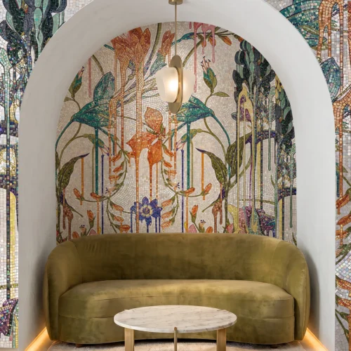 Handcrafted tropical botanical mosaic with cascading foliage and colorful flowers creating a luxury feature wall behind seating.