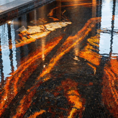 Handcrafted glass pool mosaic featuring flowing lava-inspired abstract artwork in amber, gold, orange, and black.