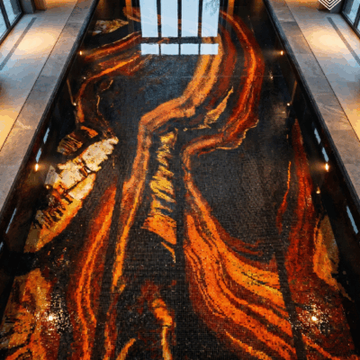 Handcrafted glass pool mosaic featuring flowing lava-inspired abstract artwork in amber, gold, orange, and black for luxury pools.