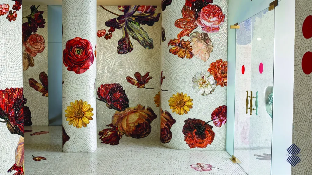 A luxury interior space featuring custom floral mosaic tile art on curved walls with red, orange, and yellow blossom patterns.