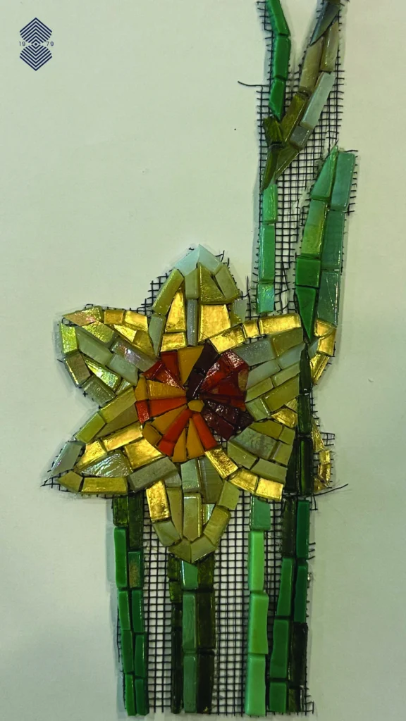A close up of a premium glass mosaic yellow flower, with green delicate branches