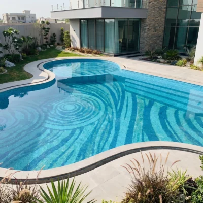 Luxury freeform swimming pool featuring a handcrafted glass and marble mosaic with flowing blue ripple patterns beneath clear water.