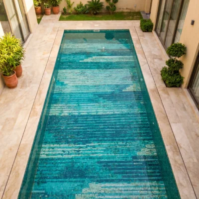 Luxury swimming pool featuring a handcrafted glass mosaic with layered turquoise, aqua, teal, and white linear patterns inspired by flowing water.
