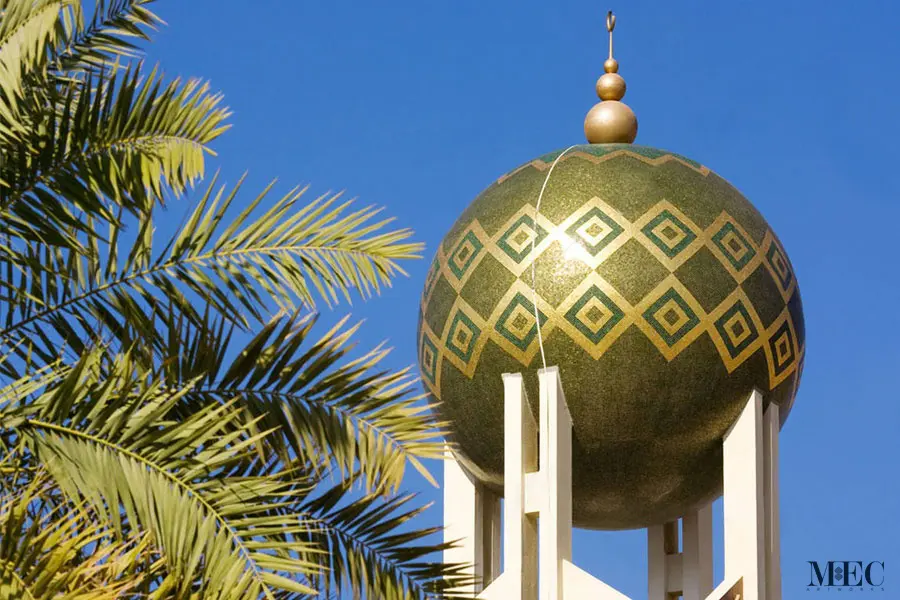 A spherical architectural element decorated with an olive green and gold diamond mosaic pattern.