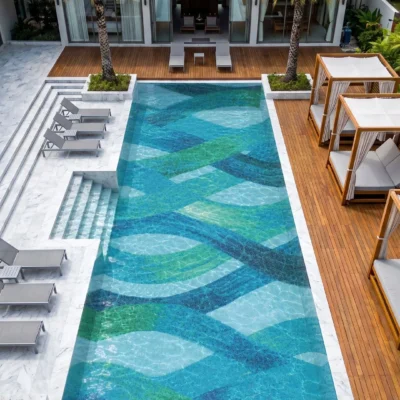 Aegean Reverie glass mosaic swimming pool featuring flowing turquoise, teal, green and blue abstract patterns in a luxury tropical setting.